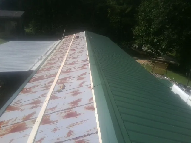 Old rusted panels beside newly installed green metal roofing — Wind Damage Roof Repair by Roofing Brothers in Mountain Home