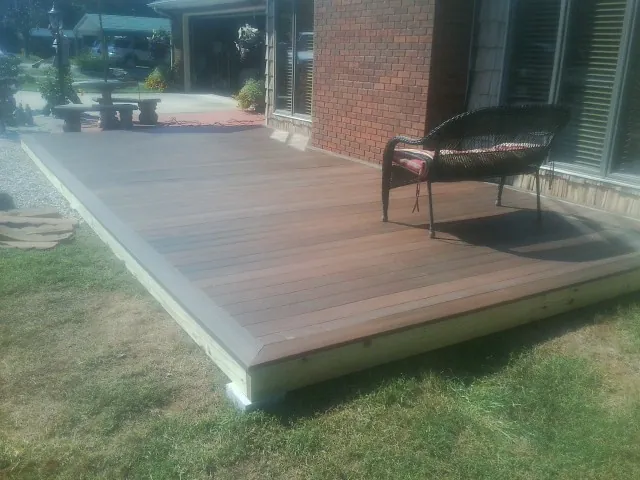New wood deck and wicker chair beside a brick house in Mountain Home